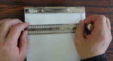 写真 点字板で点字を書いている様子。