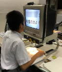 写真 卓上の拡大読書器を使用している様子。